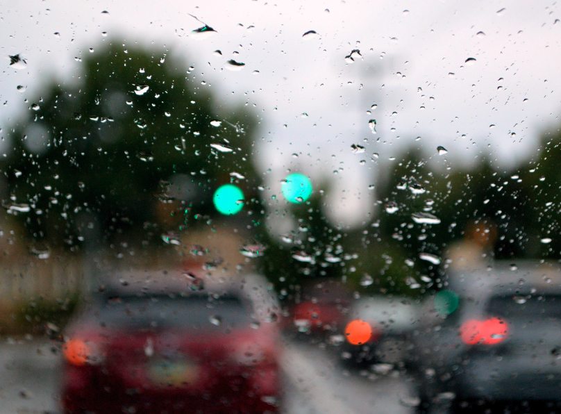 Windshield view through rain-speckled glass on a busy street in Fayetteville, AR